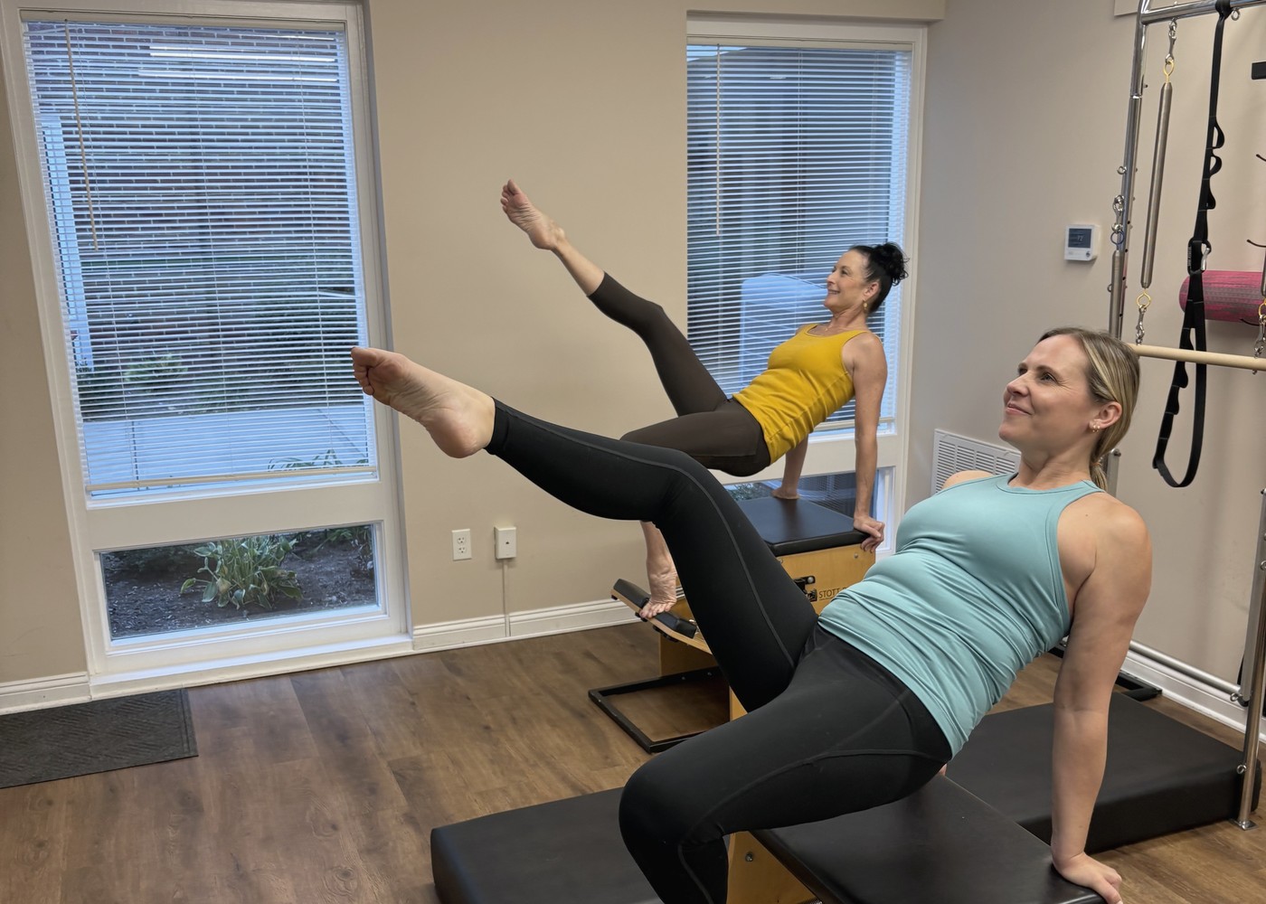 Nicole smiling during a stability chair exercise, with a client on a second chair behind her.